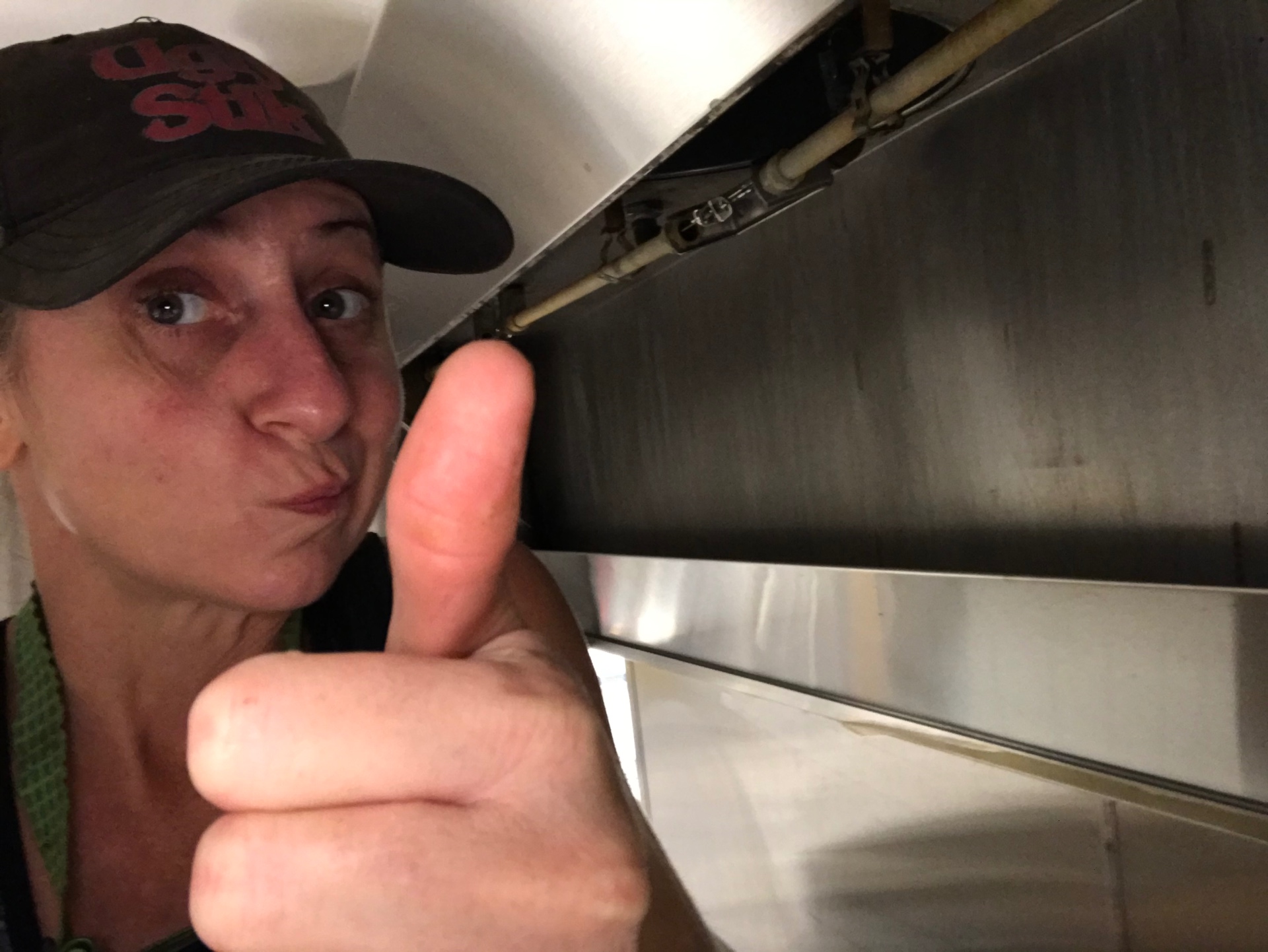 Cara giving a thumbs up under a freshly cleaned commercial kitchen hood